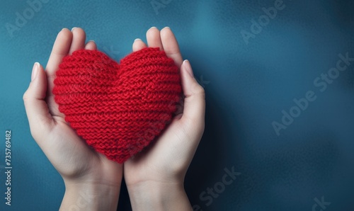 A person is shown holding a knitted heart in their hands  showcasing a heartfelt creation.