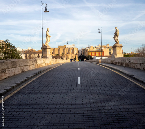 Asphalt and road over the Trinidad Bridge (15th century). The statues that adorn the entrance to the bridge are from the 17th century. Valencia, Spain. photo