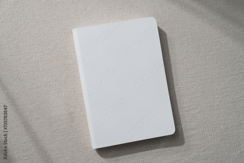 top view blank white book cover mockup on earthy neutral colors cloth background. with clipping path. top view blank white book cover mockup on earthy neutral colors cloth background. with clipping path.