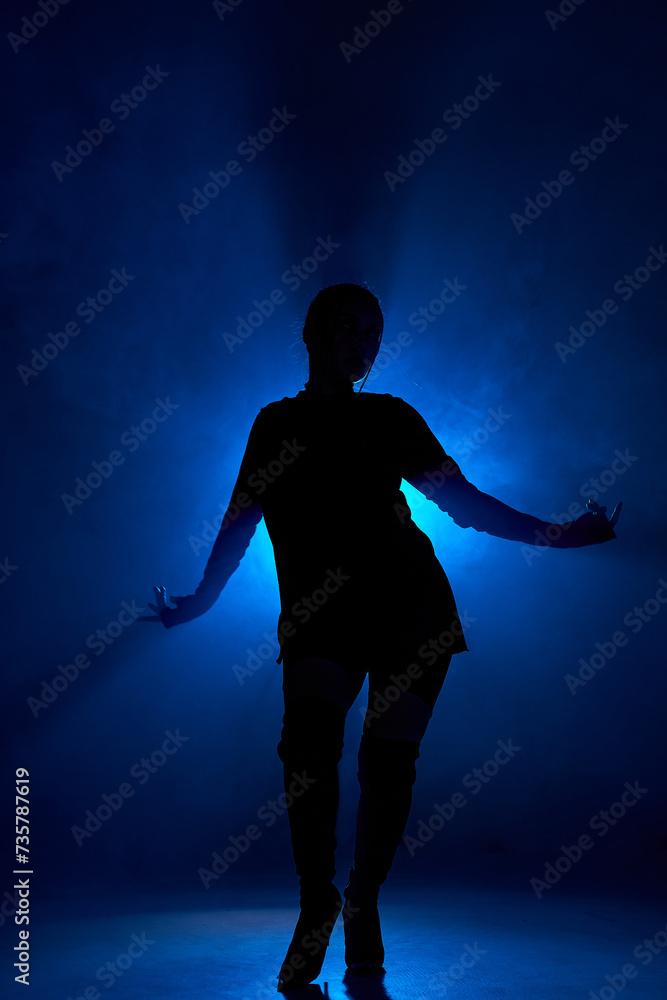 Silhoette of sexy woman dancing in dark smoky room with blue backlit. Unrecognizable lady with passionate body moving sensually alone in room, rehearsal, performance. portrait copy space