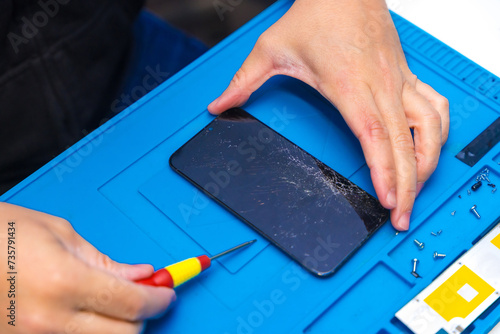 Technician using a screwdriver to open a mobile phone photo
