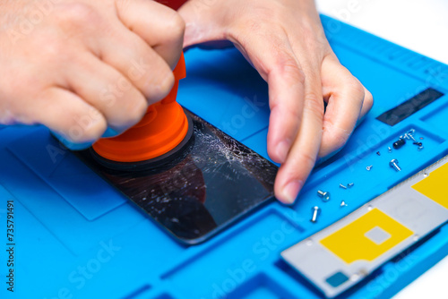 Technician using a suction cup to open a phone photo