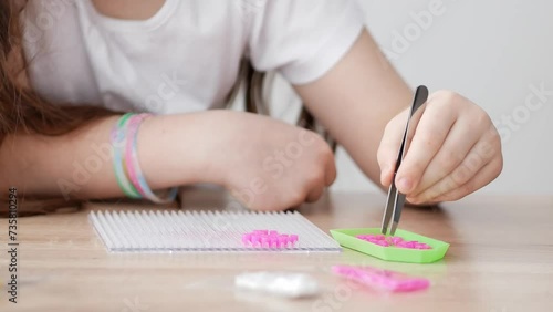 A little girl collects a toy from plastic parts of a thermal washer, works with tweezers. The first stage. Sensory education, hot plastic design, development of small psychomotor skills. photo