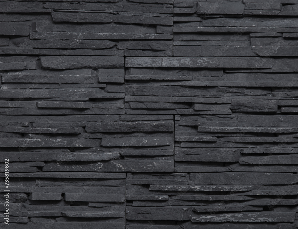 Stone cladding wall made of striped stacked slabs of black rocks. Panels for exterior. Background and texture. Stone cladding wall made of striped stacked slabs of black rocks. Panels for exterior. Background and texture.