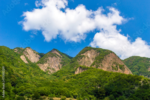 Mountains covered with green forest and blue sky with clouds