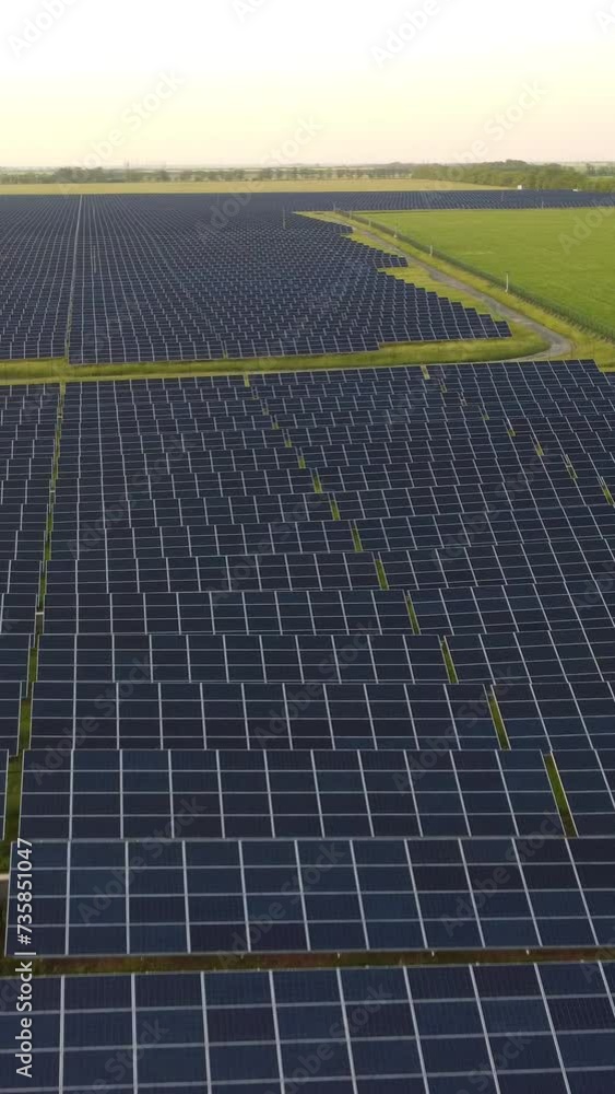 Aerial vertical view of a solar panels power plant. Photovoltaic solar panels at sunrise and sunset in countryside from above. Modern technology, climate care, earth saving, renewable energy concept. Aerial vertical view of a solar panels power plant. Photovoltaic solar panels at sunrise and sunset in countryside from above. Modern technology, climate care, earth saving, renewable energy concept.