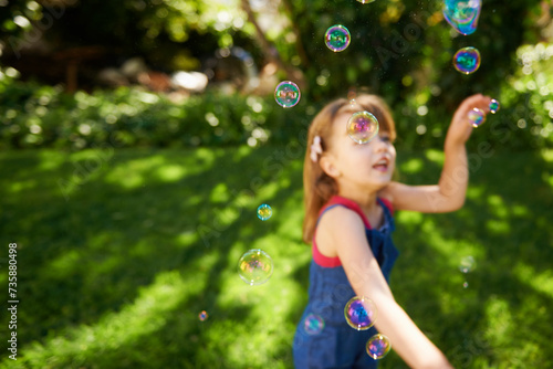 Child  bubbles and garden grass for playing in summer sunshine in backyard for holiday  carefree or happy. Kid  girl and youth in California in outdoor nature or fun for vacation  weekend or game