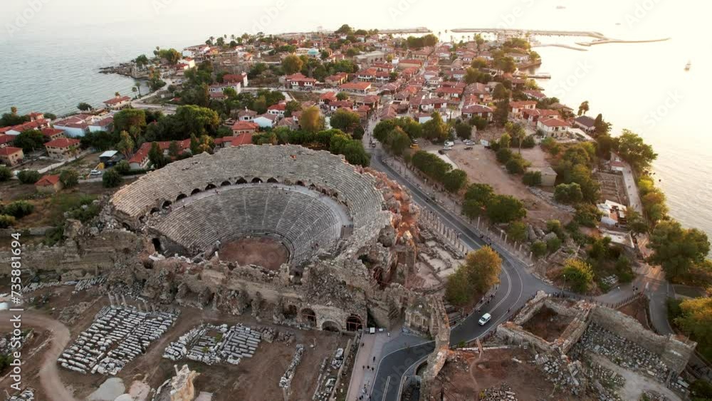 Picturesque view from drone of ruins of ancient Roman amphitheater at archaeological site in Side on background of blue water surface of Mediterranean Sea on spring day, Turkey.