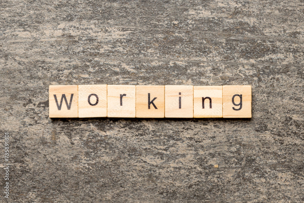 Fototapeta premium WORKING word written on wood block. WORKING text on cement table for your desing, concept