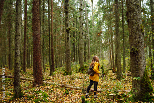 Pretty woman carrying a backpack in the forest  in the autumn season. Traveler enjoying nature. Concept of trekking, active lifestyle. Adventures.