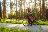 Young woman in stylish clothes rides a bicycle in a sunny park. Active lifestyle.