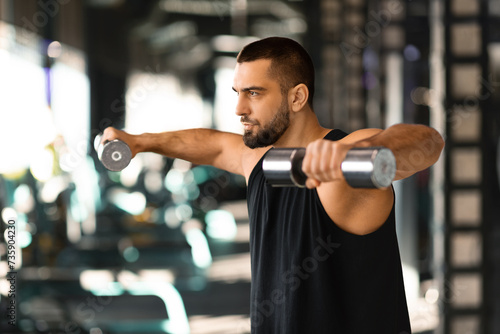 Young Muscular Man Doing Dumbbell Lateral Raise Exercise At Gym photo