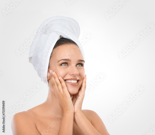 Portrait, woman and hands for moisturizing skincare with smile, head towel and white background. Mockup of female person, glow and natural makeup for self care, spa treatment and flawless skin