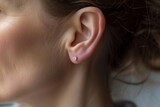womans ear with a delicate diamond stud earring visible