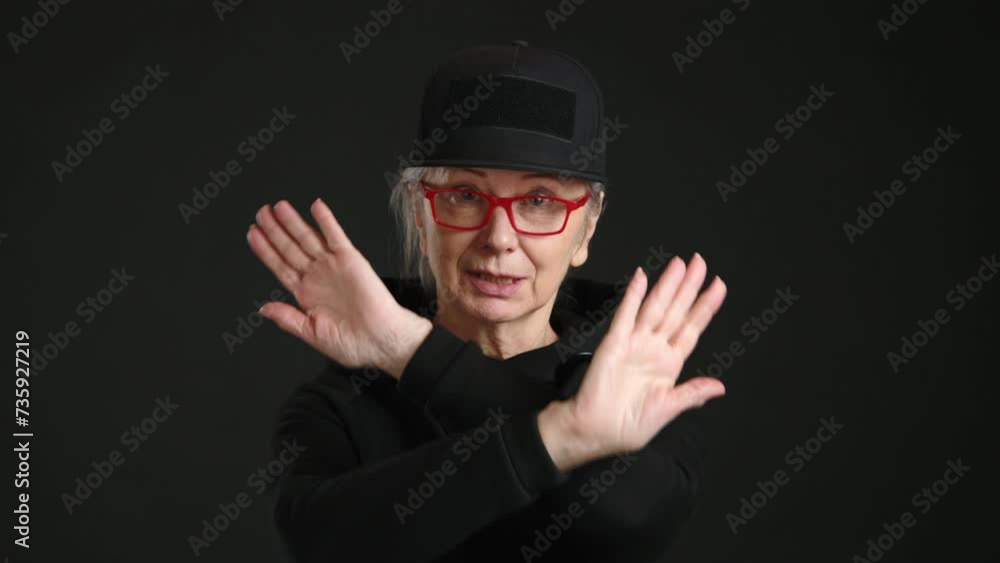 A woman donning glasses and a hat creates a stop sign by using her hands in a gesture while wearing eyewear and a cap, with a smile on her face. A woman donning glasses and a hat creates a stop sign by using her hands in a gesture while wearing eyewear and a cap, with a smile on her face.