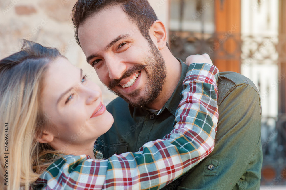 Having fun together. Close up portrait of beautiful young loving couple standing outdoors together while woman hugging her boyfriend and smiling Having fun together. Close up portrait of beautiful young loving couple standing outdoors together while woman hugging her boyfriend and smiling