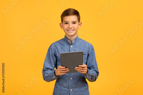 Happy teenage boy holding digital tablet in hands and smiling at camera