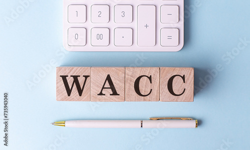 WACC on wooden cubes with pen and calculator, financial concept photo