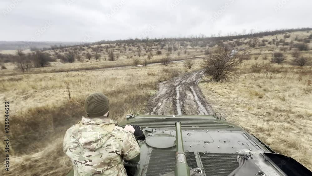 Infantry fighting vehicle with Ukrainian warrior in hatch moving along a dirt road on front line. Infantry fighting vehicle with Ukrainian warrior in hatch moving along a dirt road on front line.