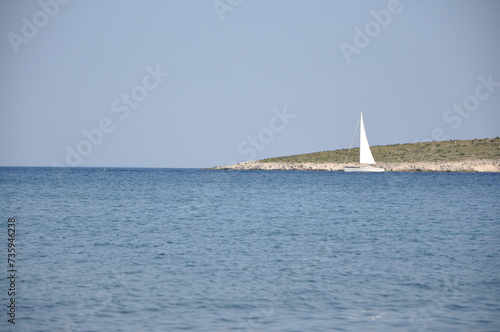 Sailing boat on the Adriatic Sea, small island and horizon in Croatian sea near Mali Losinj city.