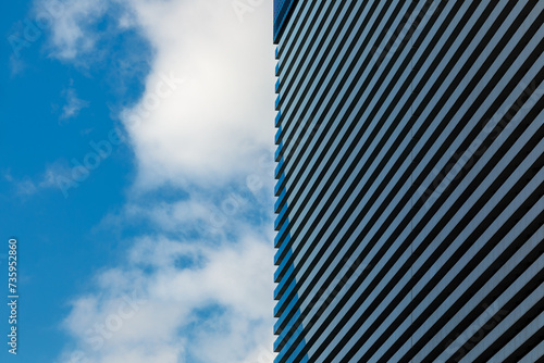 Obraz na płótnie A minimalistic photo of a part of a modern building with repetitive pattern on its exterior stands out against the partly cloudy sky w salonie