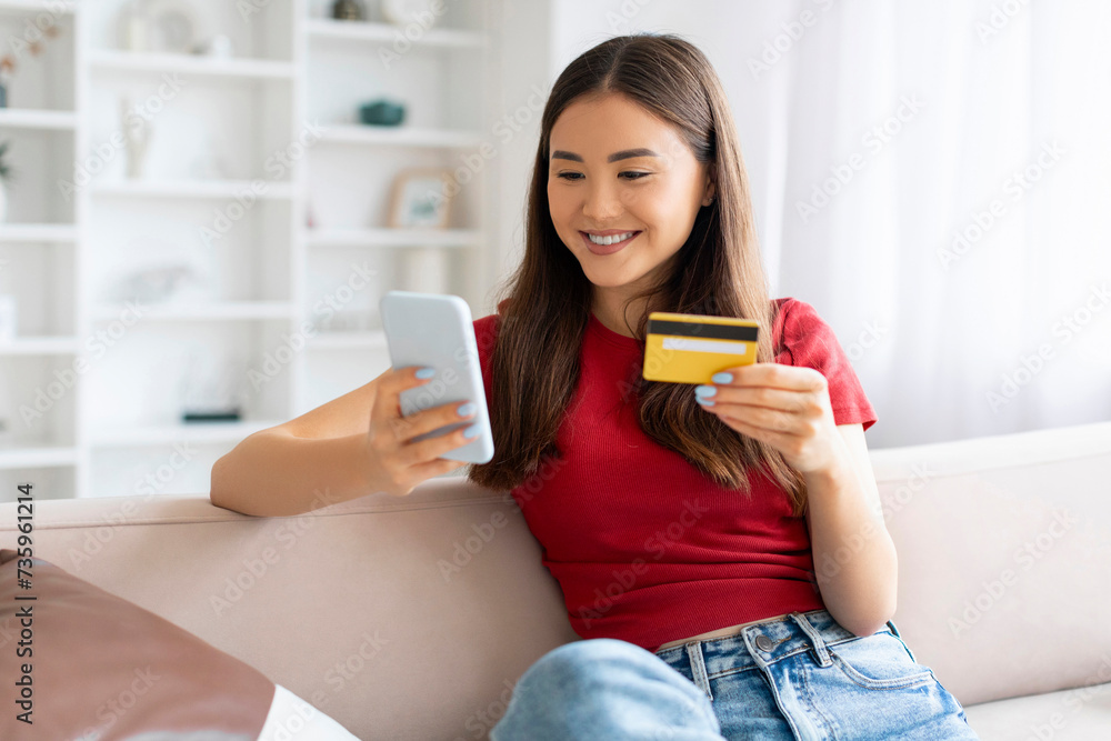 Mobile Payments. Young Asian Woman Using Smartphone And Credit Card At Home Mobile Payments. Young Asian Woman Using Smartphone And Credit Card At Home