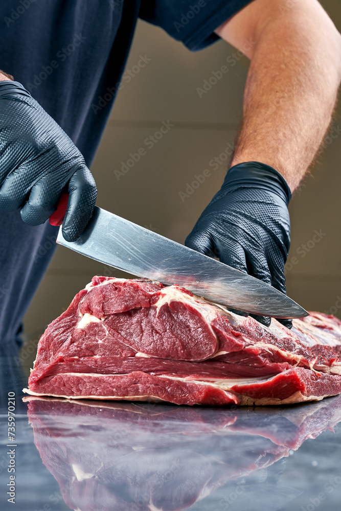 Butcher cuts a fresh piece of beef on the table