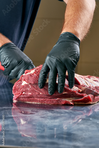 Butcher cuts a fresh piece of beef on the table