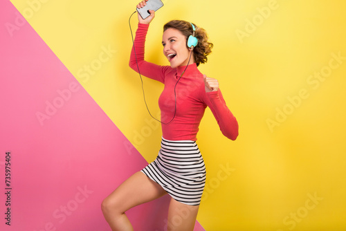 smiling attractive smiling excited woman in stylish colorful outfit dancing and listening to music