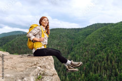 Young woman with backpack on mountain peak enjoying nature. Hiking.Travel and tourism. Active lifestyle.
