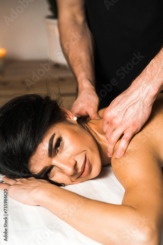 A professional masseur gives a massage to a young woman.Beautiful young woman enjoying massage in spa salon. Beauty treatment, skin care, wellbeing.Concept of massage and spa treatments