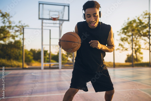 black man doing sports, playing basketball on sunrise, active lifestyle, sunny summer morning © mary_markevich
