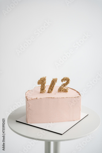 Cake. 6 month birthday cake isolated on white background closeup. Bento pink cake with decor for a six month old baby. Anniversary decor in the form of decimal meaning half of year. Space for text.