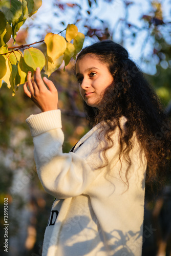 Obraz na płótnie Autumn portrait of cute 13 years old girl touching apricot leaves in sunset w salonie