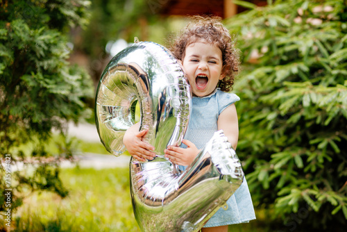 Obraz na płótnie Very happy two years old little girl celebrating her birthday, laughing, holding balloon number w salonie