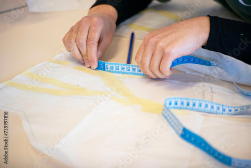 Female fashion designer working on fabric designs in her workshop. Concentrating on patterns and design. Measuring out photo