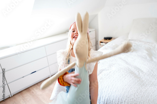 Young girl dancing in her room hugging her favourite soft toy. Bunny rabbit photo