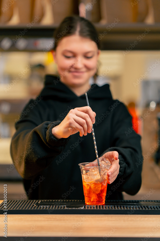 a young girl at the bar counter in the process of mixing all the ingredients of a cocktail