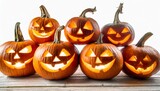 a group of eight lit spooky halloween pumpkins jack o lantern with evil face and eyes isolated against a white background