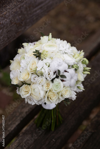 Wedding bouquet with white flowers on a wooden stairs. Bouquet with ranunculus, lisianthus, freesia and cotton flowers. © Mihai