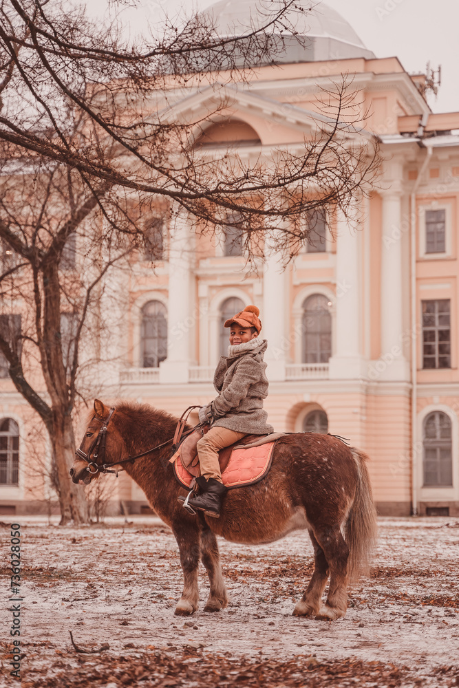 Naklejka premium boy looks around while sitting astride a pony