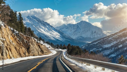 steep highway among snow capped mountains on a sunny winter day bright blue winter sky with large clouds over an asphalt road highways in usa american roads