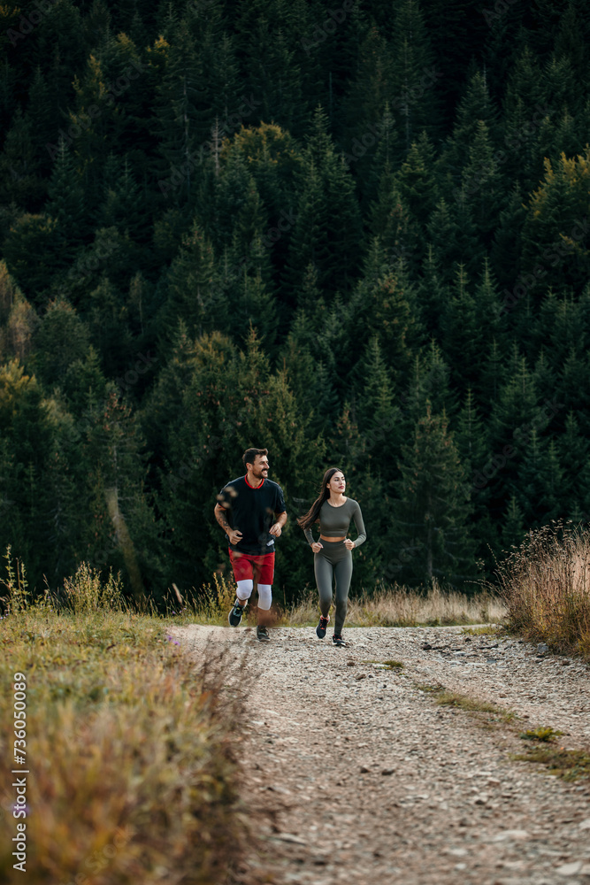 Man and woman jogging through the forested mountains in fitness gear