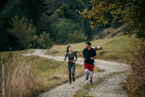 Fitness-focused couple running side by side on a mountain trail, embracing the great outdoors