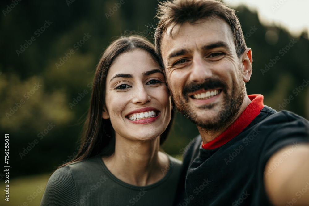 Smiling woman and man of different ethnicities snap a selfie after a refreshing jog Smiling woman and man of different ethnicities snap a selfie after a refreshing jog