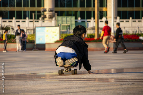 Asian child learning to skateboard, having fun and playing, children's activity and extreme sport concept. Back view. along the city street on a skateboard. I play on a skateboard. park, square © Andrei