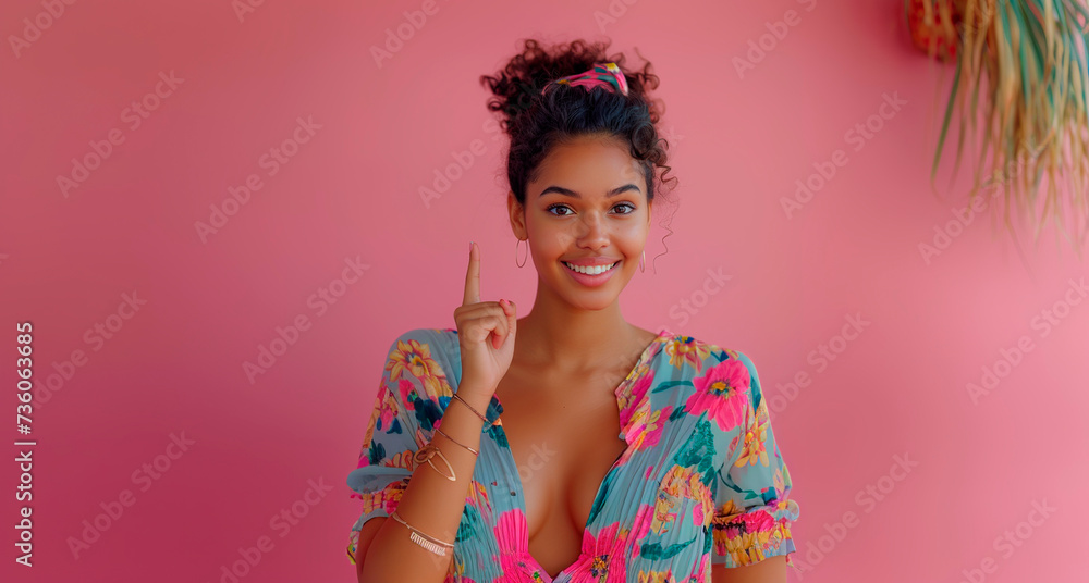 Young model in floral dress pointing up on a pink background