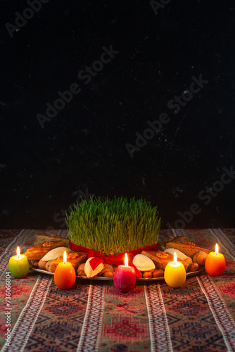 Beautiful Novruz tray on rug with semeni - wheat grass, pakhlava, shekerbura and festive candles on national Azerbaijani carpet table cloth. Spring equinox and new year celebration in Baku.