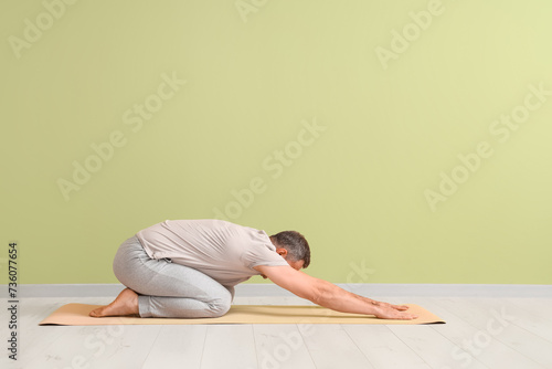 Mature man doing yoga on ma...