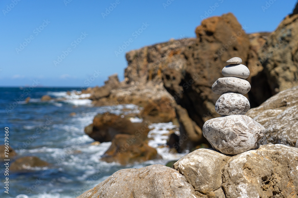 Pebbles monticules in the Papoa island in the site of geological interest of the cliffs of the Peniche peninsula, portugal, in a sunny day with the rock formations.